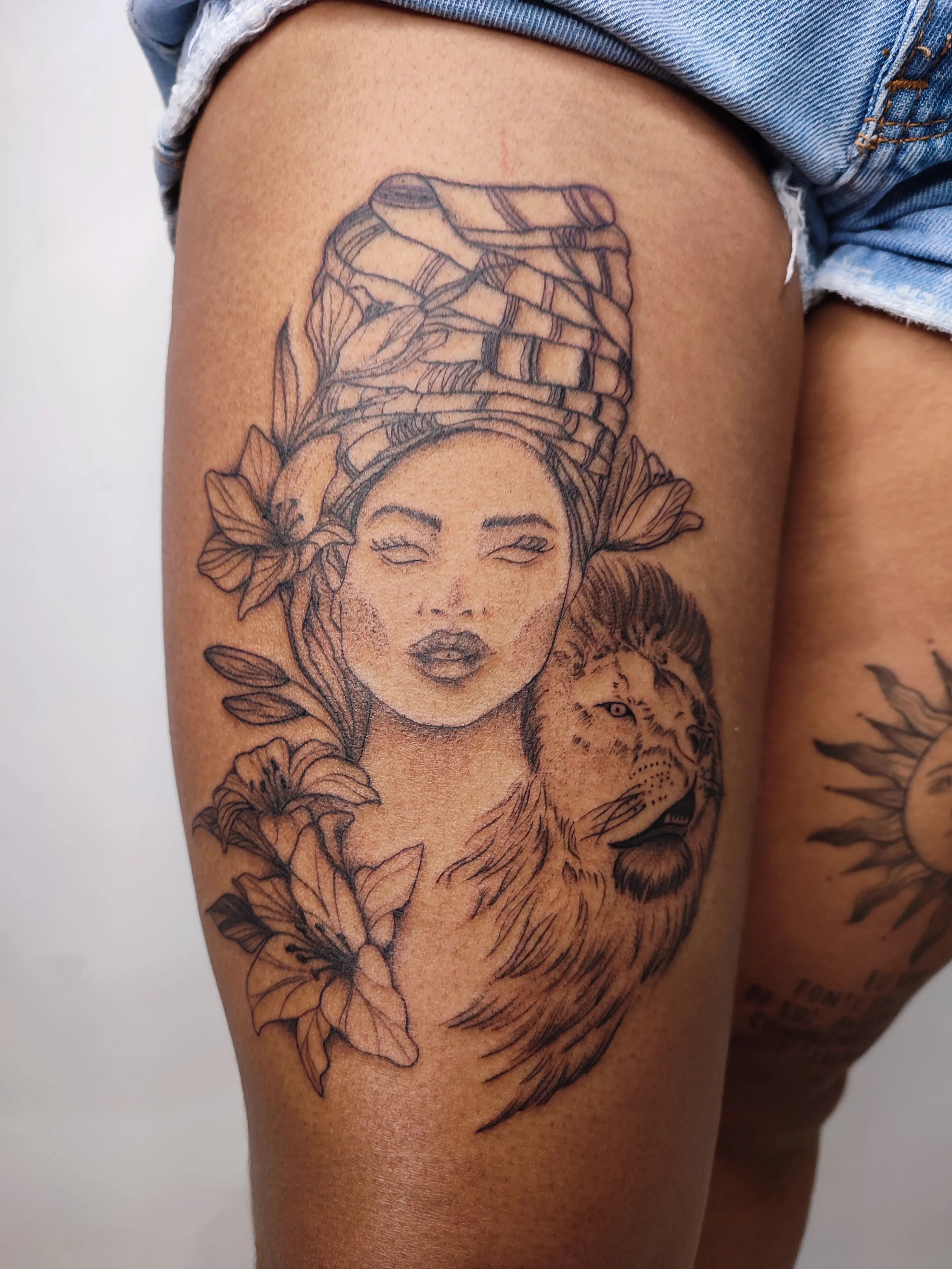 Tatuagem deuma mulher com traços mulatos ao lado de um leão