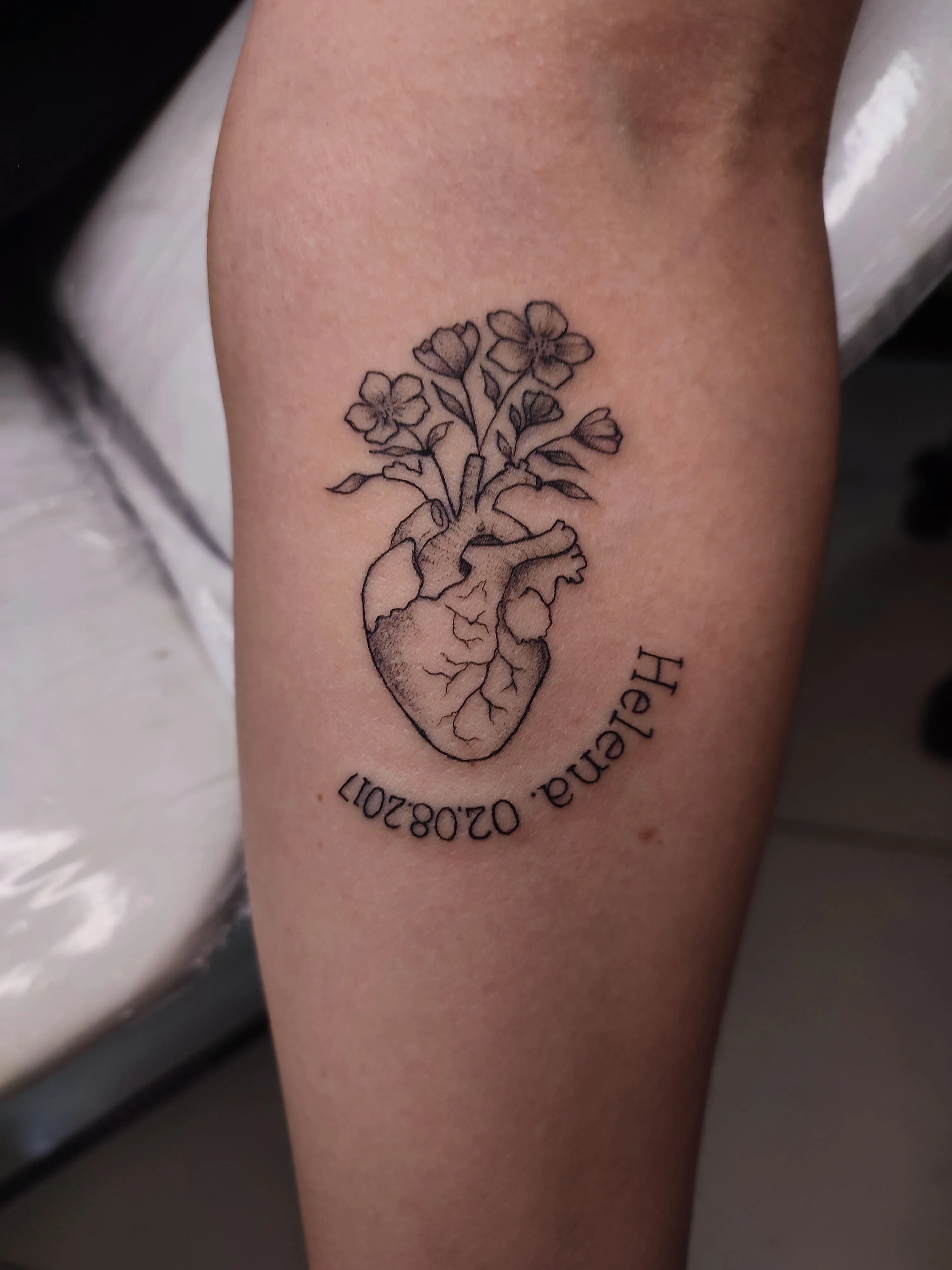 Tatuagem traço fino de um coraçao nascendo uma flor