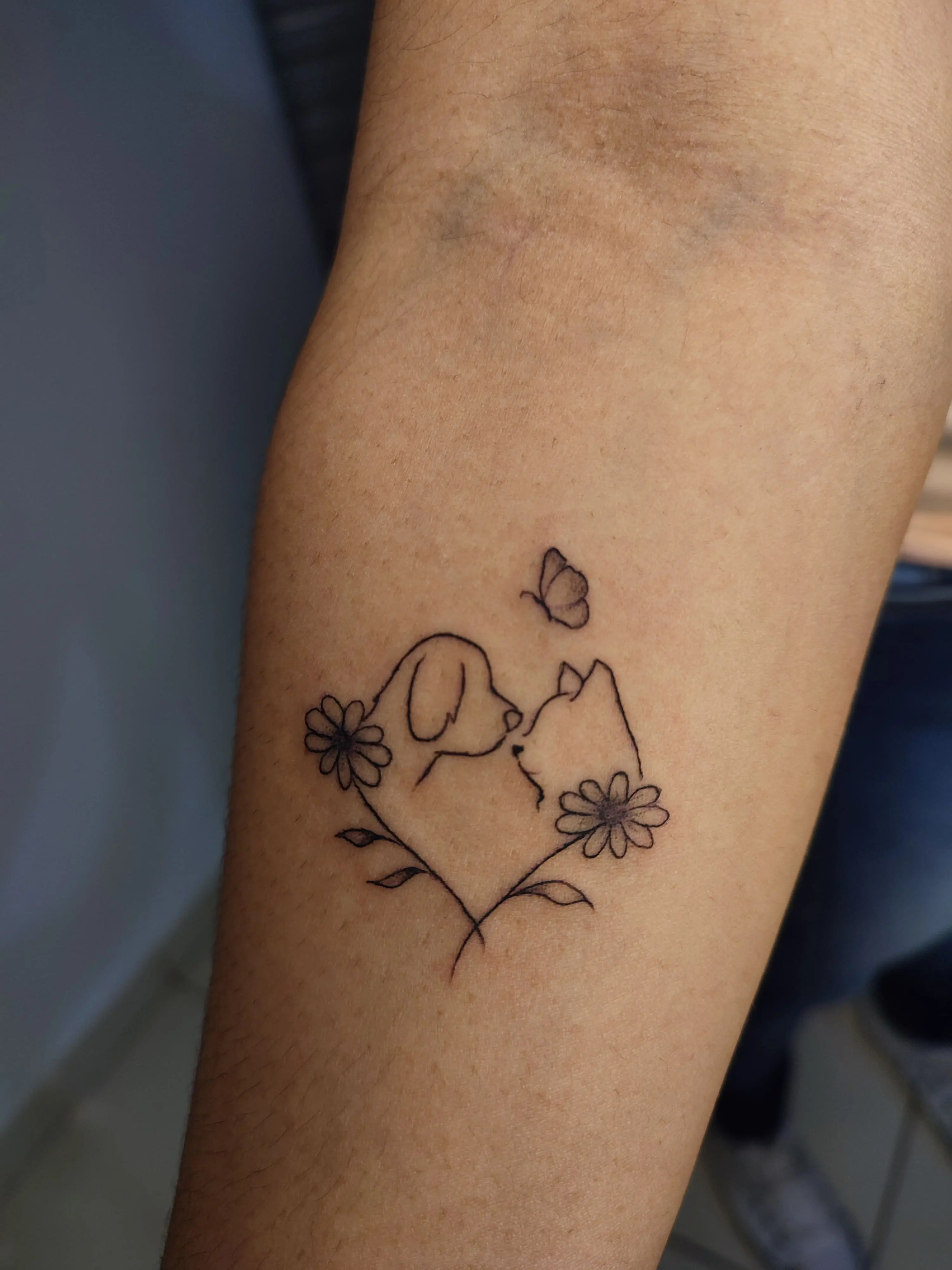 Tatuagem de uma cachorro e gato com um coraçao no meio