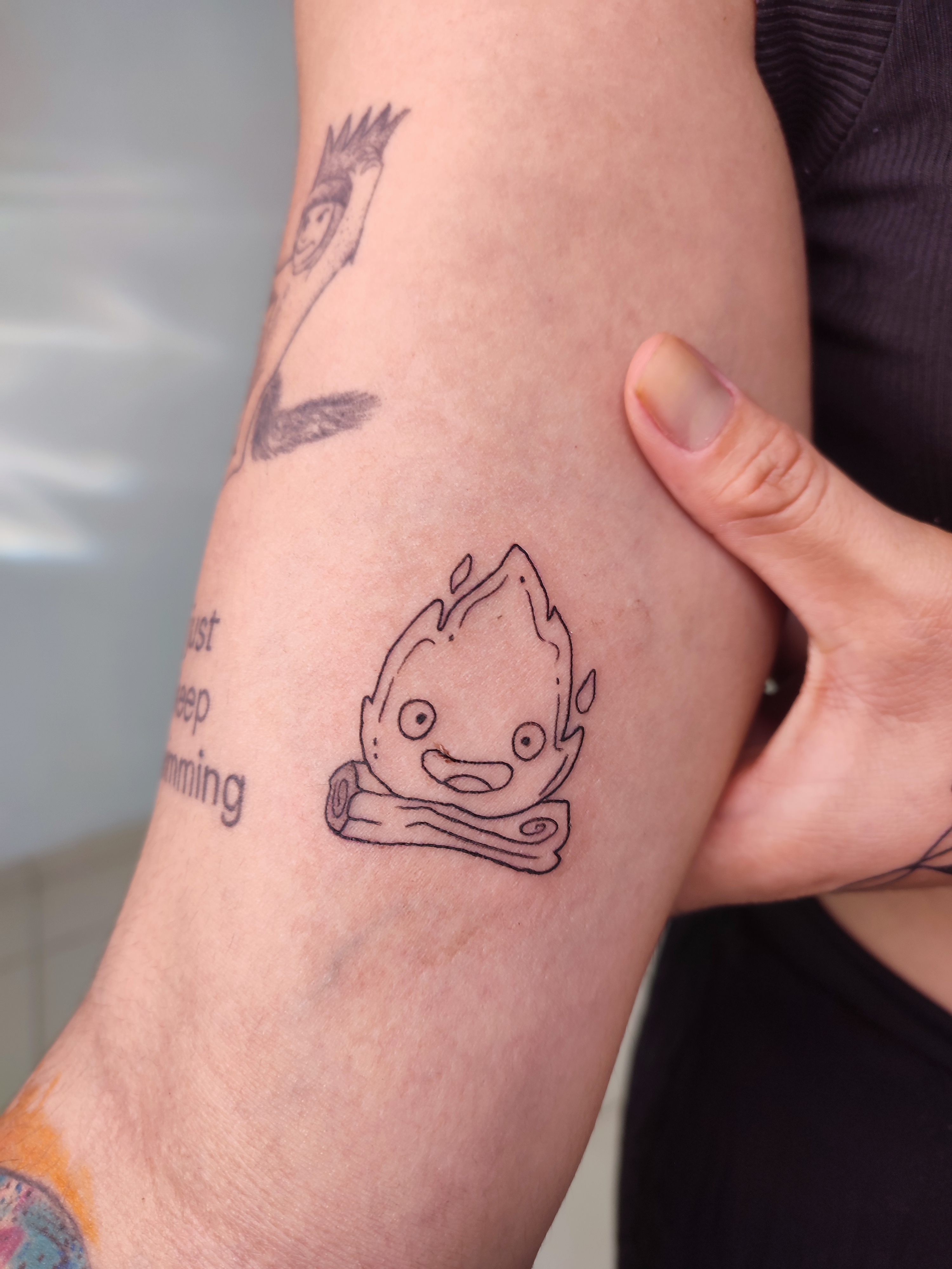 Tatuagem minimalista fogo com carinha sorridente