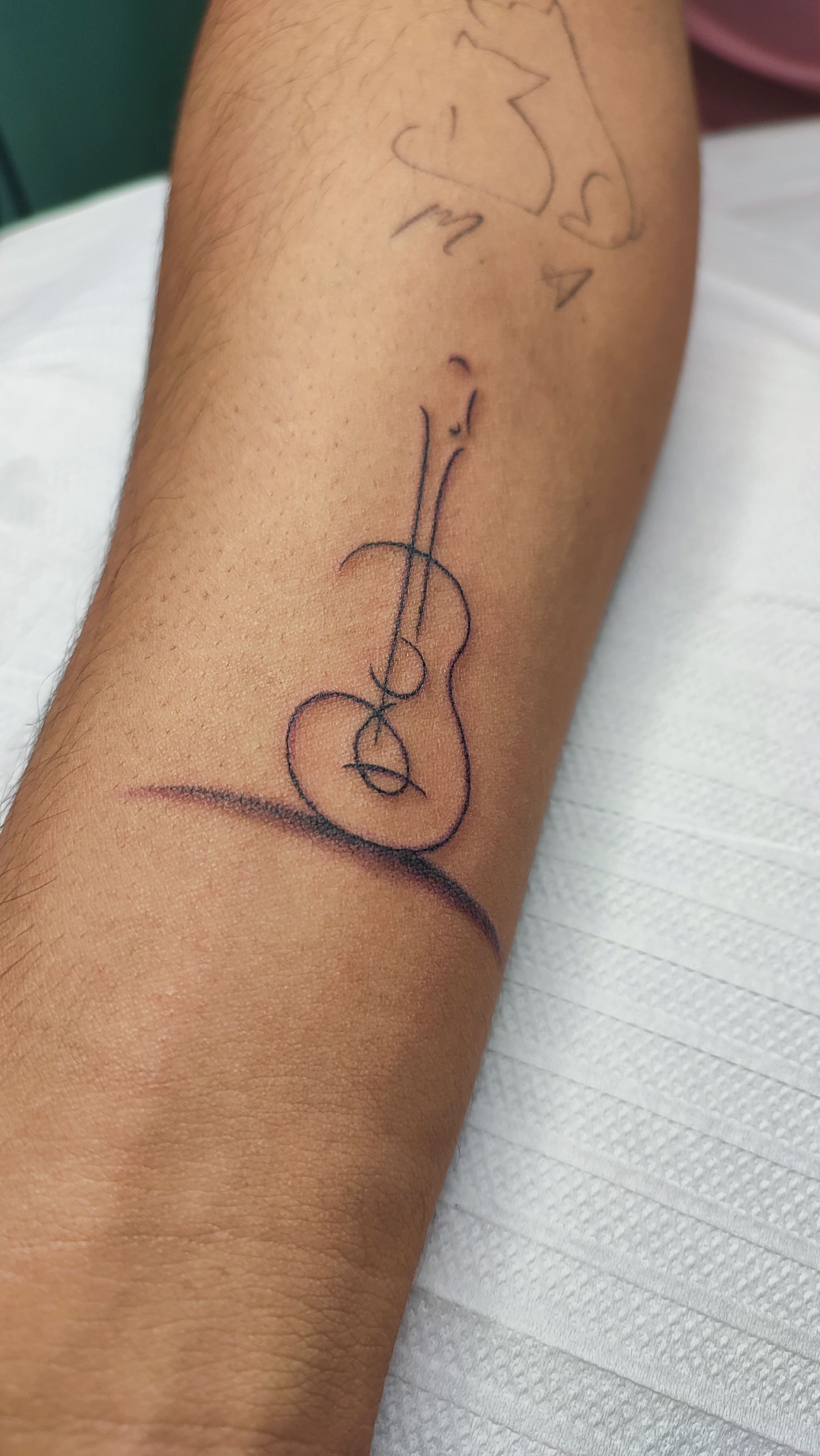 Tatuagem minimalista de um violão