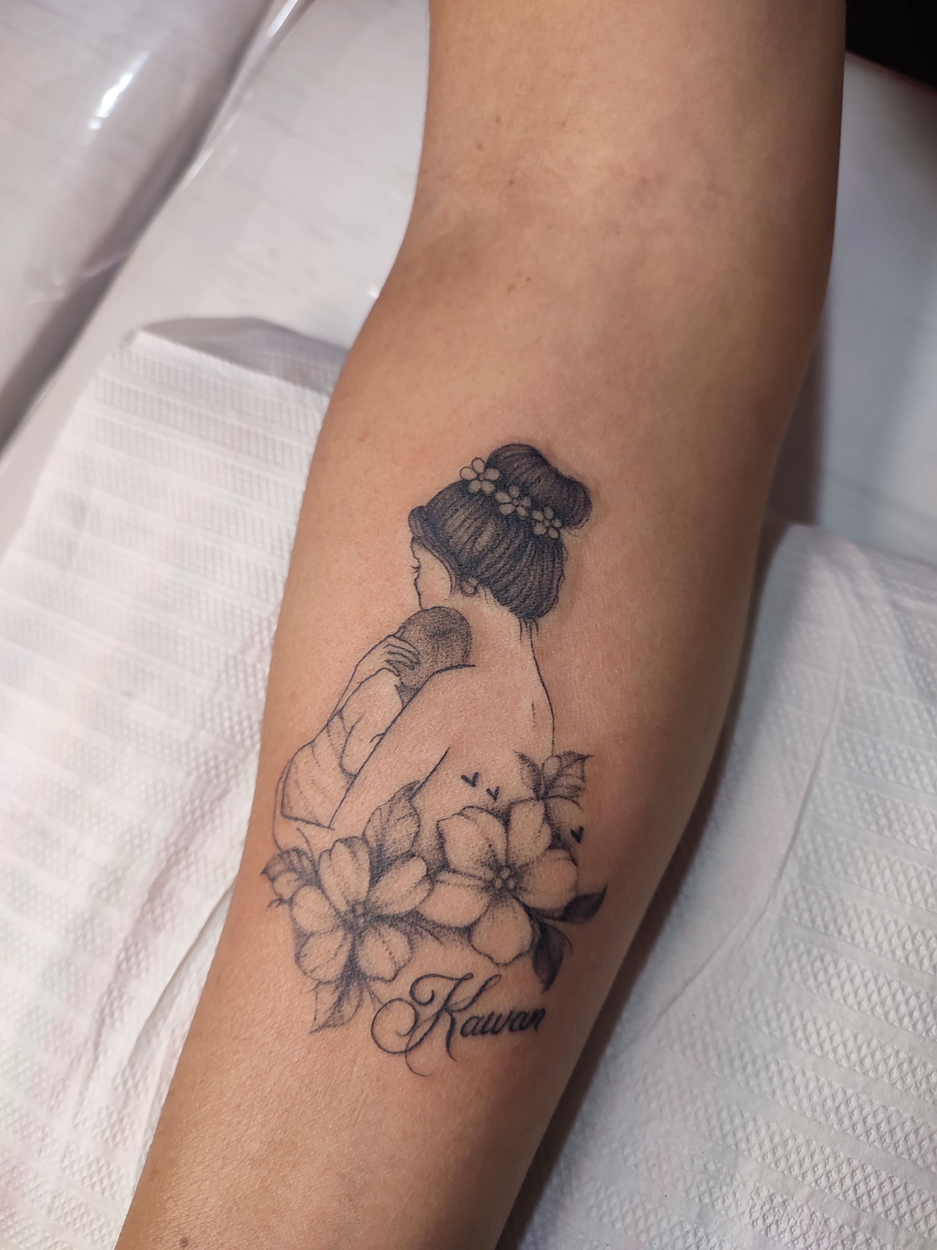 Tatuagem minimalista de uma mae abraçando seu filho, com flores em volta